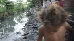 Menino fotografado em beira de rio