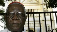 Christian Tumi poses in front of his diocese in Douala in 2004