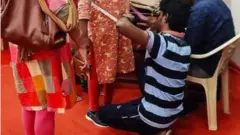 కొలతలు తీసుకుంటున్న పురుష టైలర్