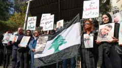 أقارب ضحايا انفجار مرفأ بيروت يحملون صورهم