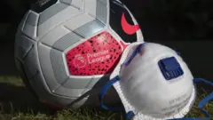 A Premier League ball next to a face mask