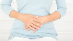 žena se drži za stomak