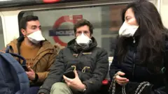 People wearing face masks on the London Underground, as the first case of coronavirus has been confirmed in Wales and two more were identified in England - bringing the total number in the UK to 19