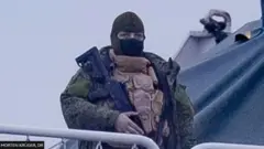 ఓడపై రైఫిల్‌తో నిల్చున్న వ్యక్తి