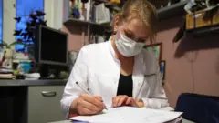 A therapist fills in a paper during a home visit to a patient.
