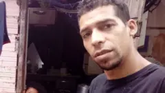André Luiz Ladanyi e seus dois filhos na frente do barraco onde família vive em Itaquera, zona leste de São Paulo