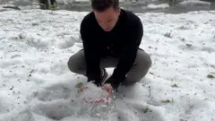 A man picking up hail stones