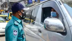 চেকপয়েন্টে একজন চালকের সাথে কথা বলছেন পুলিশের একজন কর্মকর্তা।