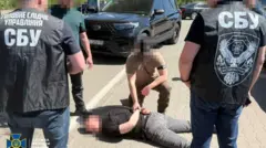 Чоловіки з заблюреними обличчями стоять біля чоловіка, який лежить на землі теж з заблюреним обличчям 