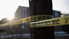 A house with a tree in the foreground with police tape