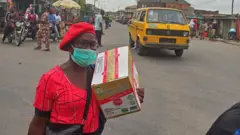 Woman wear mask carry carton for Lagos, Nigeria