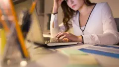Mulher entediada em frente ao computador
