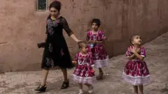 An ethnic Uyghur woman walks with her children on June 28, 2017 in the old town of Kashgar, in the far western Xinjiang province, China.