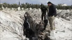 أشخاص يعدون مقابر لضحايا الزلزال في بلدة جنديرس السورية، يوم الجمعة