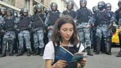 أولغا ميسيك تتلو الدستور بينما يقف العشرات من أفراد الشرطة من ورائها