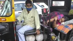 A woman lies in a rickshaw waiting for for medical assistance