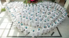 A crowd of nurses stand in the shape of a heart as they recite an oath