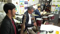 一班音樂家在香港西環一家麵館裏演奏爵士樂