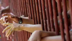 Prisioneros con sus manos saliendo por las rejas