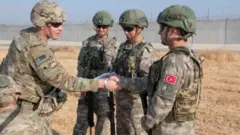 அக்டோபர் மாதம் வடகிழக்கு சிரியாவில் கூட்டு கண்காணிப்பில் அமெரிக்க மற்றும் துருக்கிய ராணுவத்தினர்.