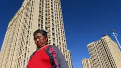 A woman walks in front of a housing complex by Chinese property developer Evergrande in Beijing
