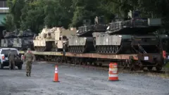 Two M1A1 Abrams tanks and other military vehicles sit on guarded rail cars at a rail yard on July 2, 2019 in Washington, DC