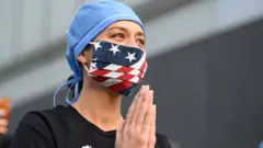 A nurse in New York reacts as people applaud medical workers
