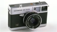 An Olympus-35 ECR rangeinfer-style camera with a short "pancake" lens is seen here against a white background