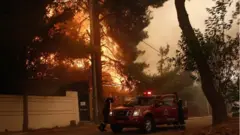 Firefighters at work to extinguish a wildfire in the area of Stamata
