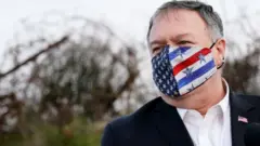 Mike Pompeo wearing a face mask with a US flag on it, standing in the occupied Golan Heights