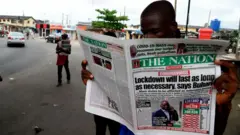 Man reading newspaper in Lagos street