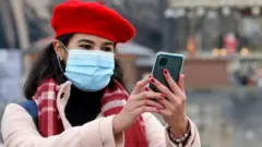 A woman wearing a protective face mask takes a selfie in front of the Eiffel Tower in December