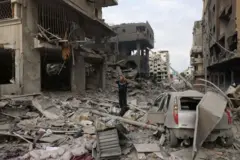 Homem palestino caminha entre escombros em meio à destruição causada por ataques aéreos israelenses no bairro de al-Rimal, na cidade de Gaza, no início de 10 de outubro de 2023