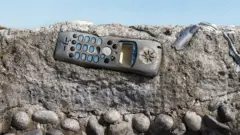 Teléfono antiguo incrustado en una capa de hormigón