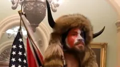 Jacob Anthony Chansley is alleged to be the man seen wearing horns and a fur hat in photographs, including this from inside the Senate chamber