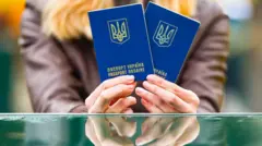 Жінка тримає два українських паспорти, її обличчя не видно