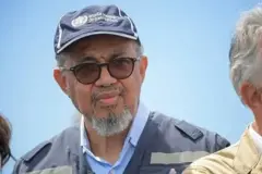 Umukuru wa OMS Dr Tedros Adhanom Ghebreyesus yambaye ingofero y'ubururu yanditseho, mu Cyongereza, Ishami ry'Umuryango w'Abibumbye ryita ku buzima.