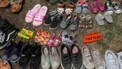 Children's shoes are placed at the base of a statue in Toronto