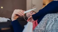 Joven en la cama con un termómetro