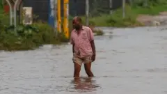 Un hombre camina en una calle inundada