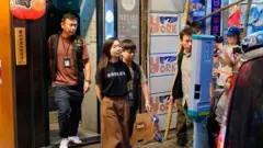 Uma funcionária é escoltada para fora da livraria independente Have a Nice Stay pela polícia de segurança nacional de Hong Kong.