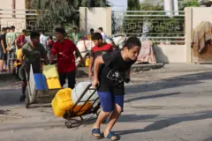 طفل فلسطيني يحمل عبوات المياه في قطاع غزة