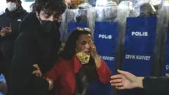 People help a woman affected by tear gas in Istanbul