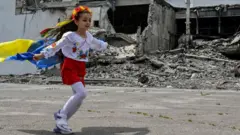 Украинка с флагом на фоне разрушений