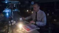 A man reads a newspaper by candlelight during the blackout in Argentina