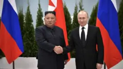 El líder de Corea del Norte, Kim Jong Un (izquierda) en un encuentro con el presidente de Rusia Vladimir Putin (derecha) in Vladivostok, Rusia en 2019 con banderas de ambos países al fondo.