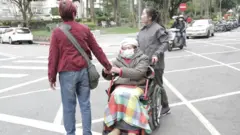 Muji wheels Ana's wheelchair across the road.