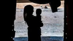kampta bir kadının kucağında bir bebek