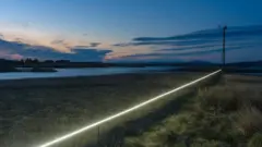 Foto artística, com paisagem de céu, grama e um facho de luz