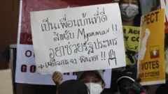 A demonstrator holds a placard reading "A good neighbour will not support a military coup" during a protest against the Myanmar military coup, outside the Embassy of Thailand in Yangon, Myanmar, 24 February 2021.